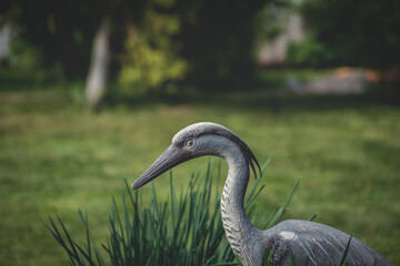 Bird statue in the garden. Artificial figure of a bird on a green background.