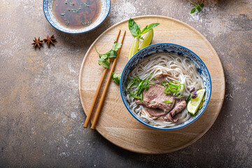 Top view of pho bo vietnamese rice noodle soup with herbs and sauce