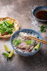 Pho bo with beef tonque, herbs, spicy sauce and lime - 438573930