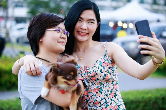Happy memories. Delighted positive lesbian couple smiling while taking photos together with her dog