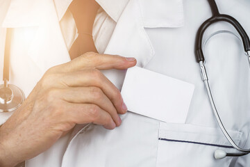 Wrinkled fingers of senior doc shows blank white card take it from pocket