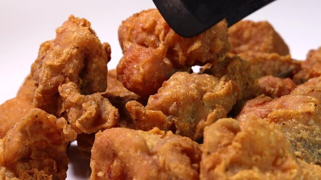 Light battered deep fried chicken variety mix pieces pile flaky meat on white background pick drop fork 
