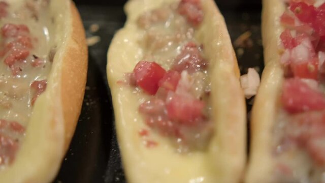 Spoon adding pico de gallo to traditional Mexican molletes above black tray