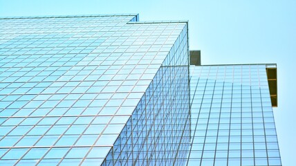 Fototapeta na wymiar Blue sky and clouds reflected in windows of modern office building. Modern glass facade. 