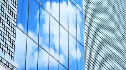 Fototapeta na wymiar Blue sky and clouds reflected in windows of modern office building. Modern glass facade. 