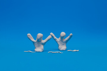 Two white modeling clay dummies practicing synchronized swimming