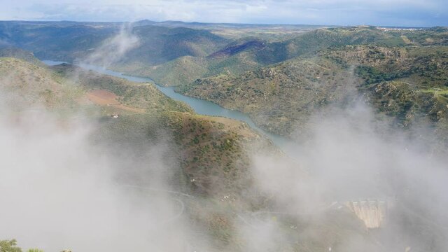 Mountain and Douro river with spanish Saucelle Dam at foggy cloudy weather. Border between Portugal and Spain. National Parks. View from portuguese Penedo Durao lookout.