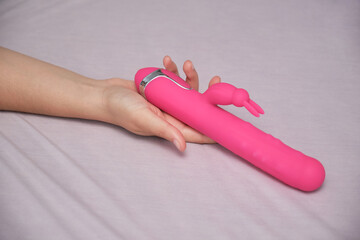 Unrecognizable woman holding a dildo in bed
