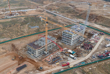 Tower cranes in action at construction site. Crane during formworks. Soil Compactor leveling ground...