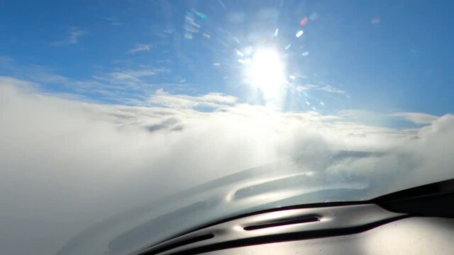 Plane flies through the clouds. Cocpit view. Blue sky and sun. 