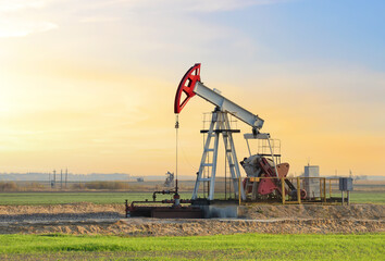 Crude oil pump jack at oilfield on sunset backround. Fossil crude output and fuels oil production....