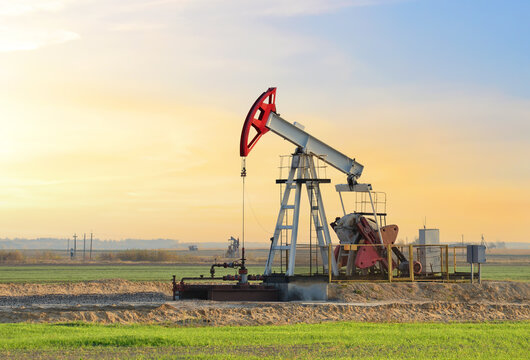 Crude oil pump jack at oilfield on sunset backround. Fossil crude output and fuels oil production. Oil drill rig. Crude mining concept. Oil prices on the trading exchange.