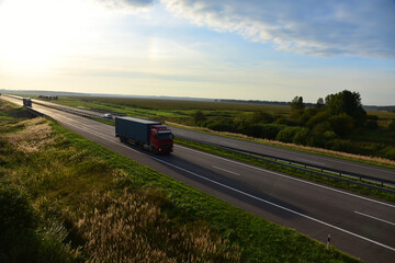 Semi truck transporting sea container on highway on sunset background. Shipping Containers Delivery, Maritime Services and Transport logistics. Shipping Container on lorry. Semi-tractor-trailer truck