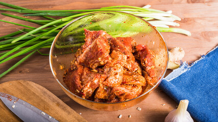 Cooking Chinese food pork. chopped pieces of pork with Sichuan pepper sauce, chopped ginger and garlic in a bowl on the table.
