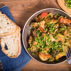Vegetarian home cooking. vegetable stew of zucchini, broccoli, tomato with green onions in a plate on the table with slices of bread, top view