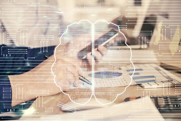 Double exposure of man's hand holding and using a digital device and brain hologram drawing. Data...