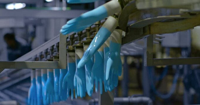 Silicone medical gloves on plastic molds rotate on a conveyor belt, modern equipment in the workshop. Silicone gloves manufacturing process, factory. 4k, ProRes