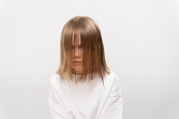 sad little girl with hair covers the face on a white background.