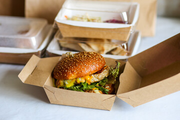 Food delivery in boxes. Delivery to the office. Food in boxes.Fast food delivery. Burger delivery.Burger in a carton box. Burger with soy cutlet. Vegetarian burger delivery.Office food.Takeaway food