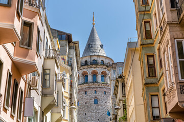 Obraz premium Famous tourist place Galata tower seems between old traditional buildings. Empty street, no people. Istanbul during coronavirus lockdown.