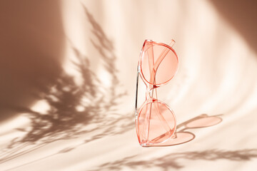 Fashionable pink sunglasses on floral background. Pampas grass natural shadows on beige background. Concept of summer accessorize