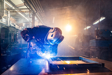 Two handymen welding and grinding metal at workshop