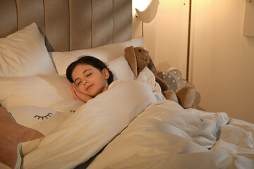 Little girl sleeping in bedroom lit by night lamp