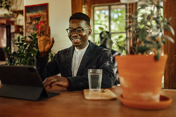 Elegant man, waving to his coworkers online.