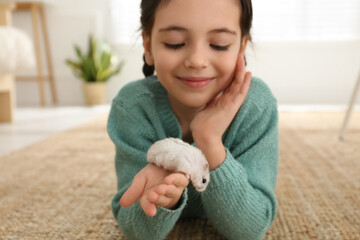 Little girl with cute hamster at home