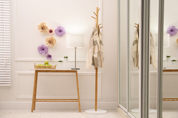 Stylish room interior with floral decor and table near wardrobe