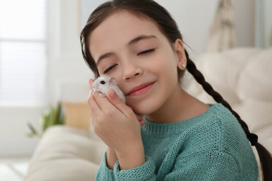 Little girl with cute hamster at home