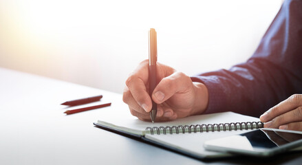 Businessman hand holding writing pen memo into notebook paper on table desk office. Workplace for business and student, writer with copy space. business working and learning education concept.