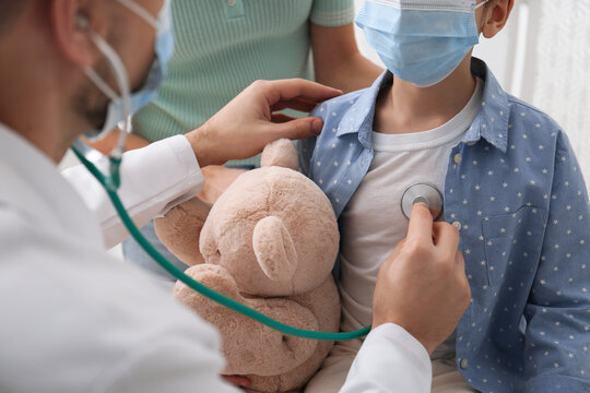 Pediatrician examining little girl in hospital. Wearing protective masks