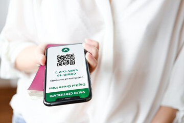 Unrecognized woman holding smartphone with digital green pass and QR code on the screen. Health passport or certificate of immunity. Traveling without restrictions. Vaccinated person