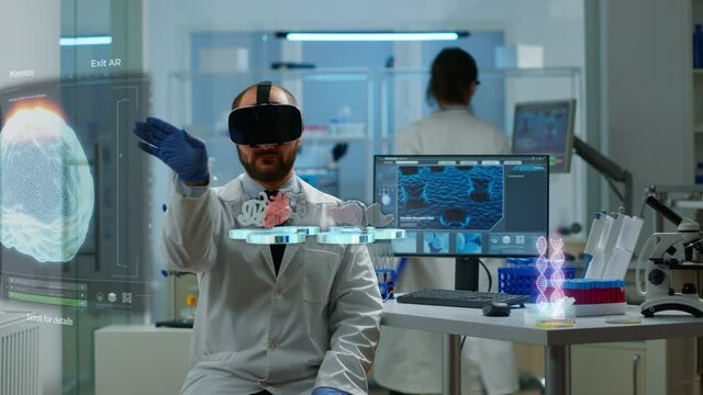 Male scientist in lab wearing VR goggles working on augmented reality virtual holograms. Lab research with 3D render futuristic holograms, health care scientific. VFX and real medical doctor footage
