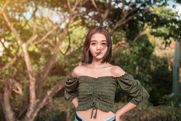 A confident young asian lady wearing a green off shoulder blouse during a windy day at the park...