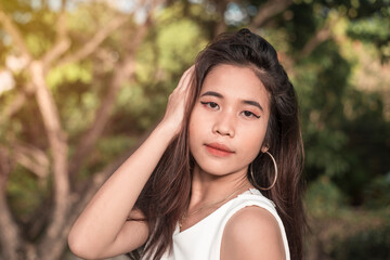 A slim, petite and pretty young Chinese Filipina wearing a white sleeveless blouse at the park.