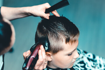 Fototapeta premium Cute kid have hair cut,professional barber doing haircut. Hairdress for children. side view portrait barbershop.Toned