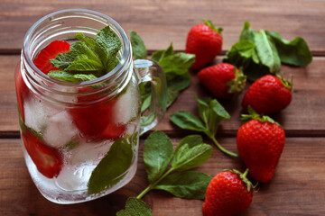 Fresh strawberry lemonade with ice and mint in jar on the wooden table. Summer refreshment drinks. Close-up, selective focus