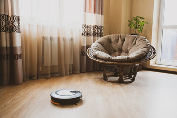 Robot vacuum cleaner in a room in new apartment cleans the laminate floor. Concept of homework and technology