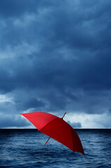 red umbrella into sea with a stormy sky approaching