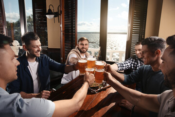 Friends clinking glasses with beer in pub
