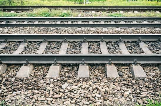 Closeup of metal railway track with concrete railroad ties on ballast stone