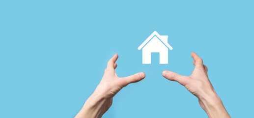 Fototapeta na wymiar Male hand holding house icon on blue background. Property insurance and security concept.Real estate concept.