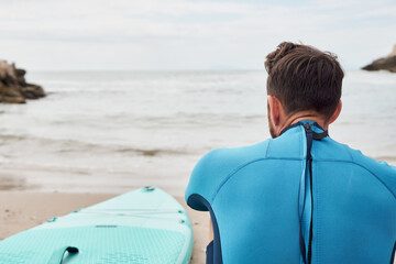 Fototapeta premium Man looking at the sea with paddle board