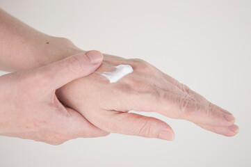 Close up of arm of young woman applying cream on her hand