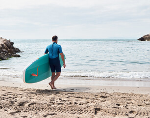 Surfer entering the water with a paddle board