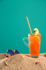 Product of CBDa oil, orangeade or ice tea in a jar and seashell on sand