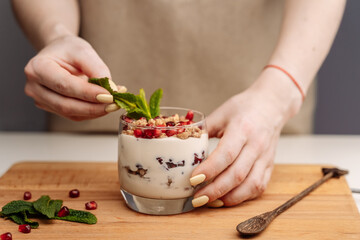 Female hands preparing yogurt with Strawberry for good digestion, functioning of gastrointestinal tract. Summer berries, nuts, fruits, dairy products on table. Healthy food concept.