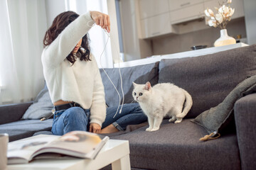 A woman in a white sweater playing with her cute pet